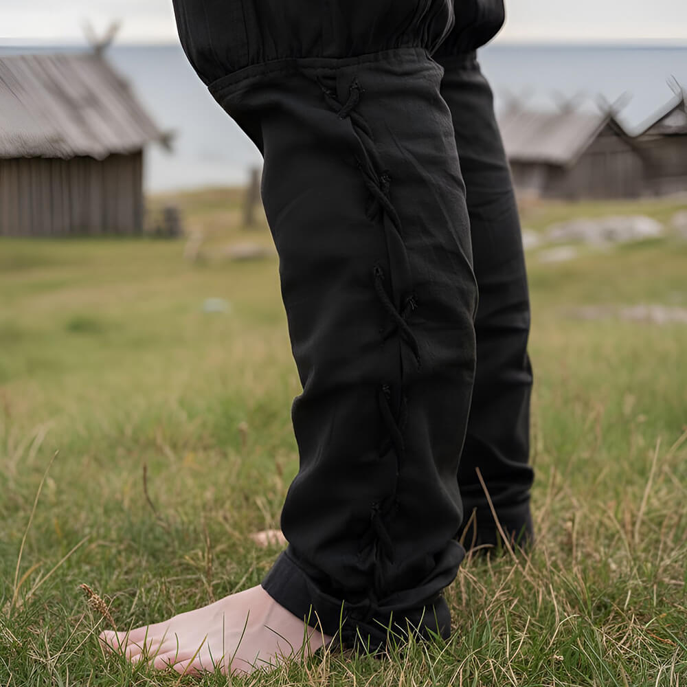 Black cotton Renaissance trousers with drawstring waist and calf lacing, worn outdoors.