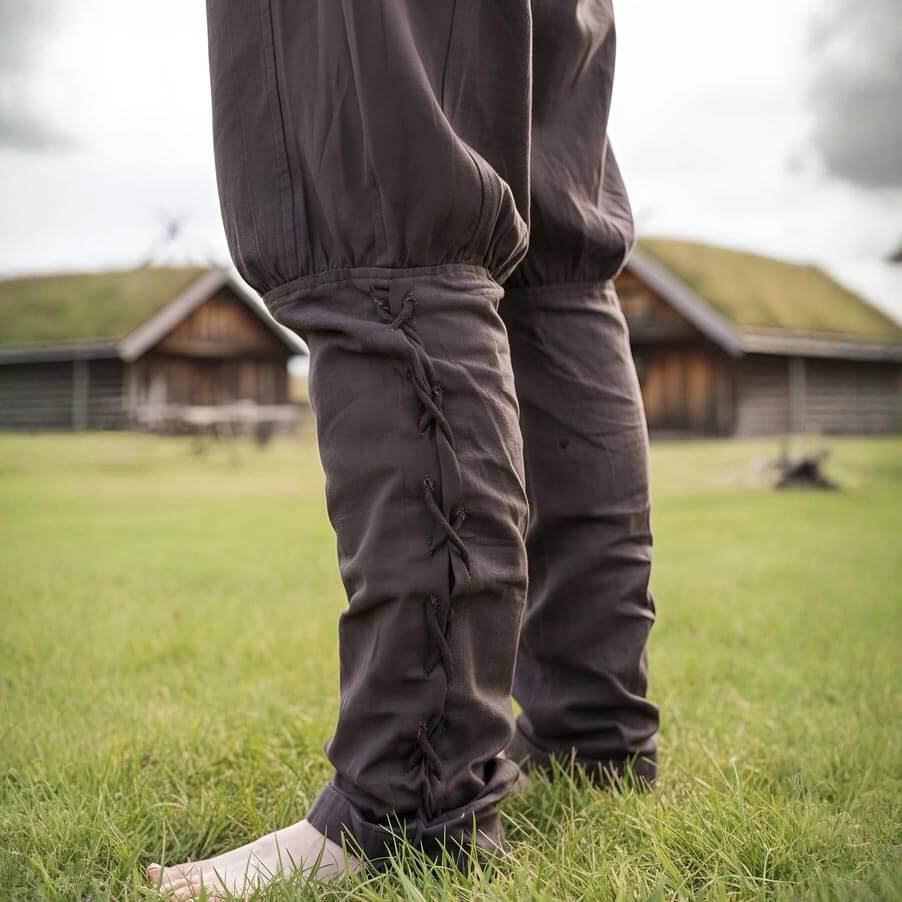 Brown cotton Renaissance trousers with drawstring waist and calf lacing, worn outdoors.
