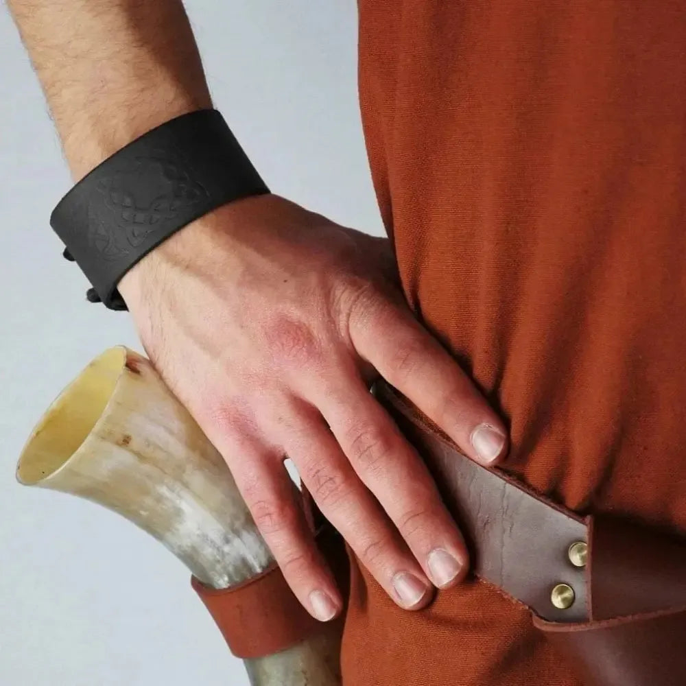 Black cowhide leather Renaissance bracelet with Celtic knotwork embossing on a man's wrist.