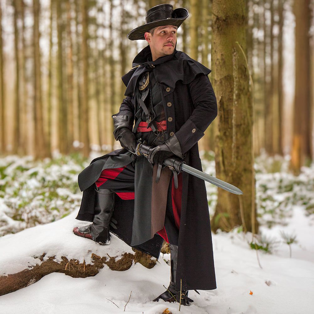 Renaissance black canvas pirate overcoat with ornate buttons, shoulder mantle, and hat in a snowy forest.