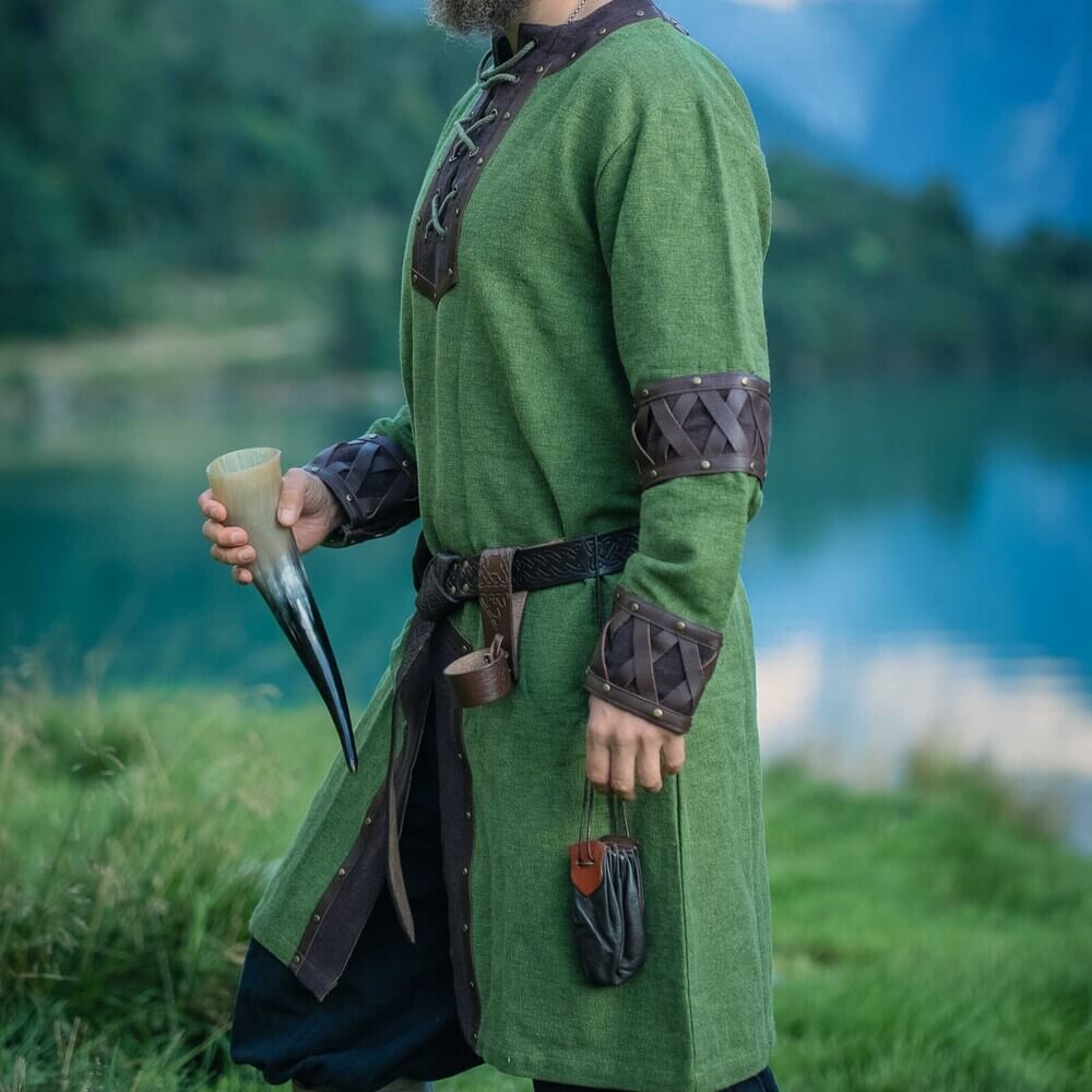 Green Renaissance tunic with ornate crisscross leather trim at V-neck, cuffs, and hem.