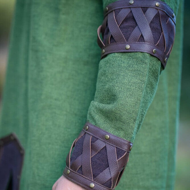 Renaissance green cotton tunic sleeve with ornate brown leather X-pattern cuffs and arm trim secured by rivets.