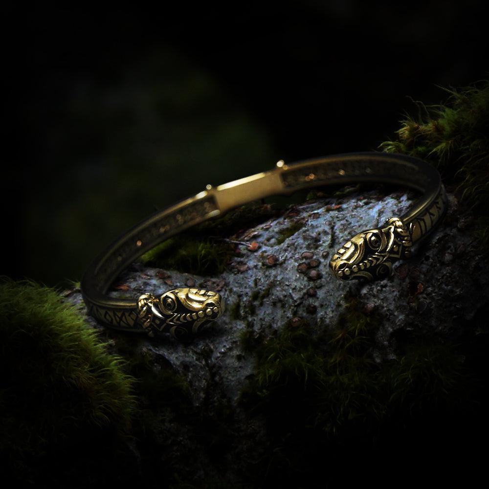 Renaissance bronze serpent bracelet with engraved runes, resting on mossy wood.