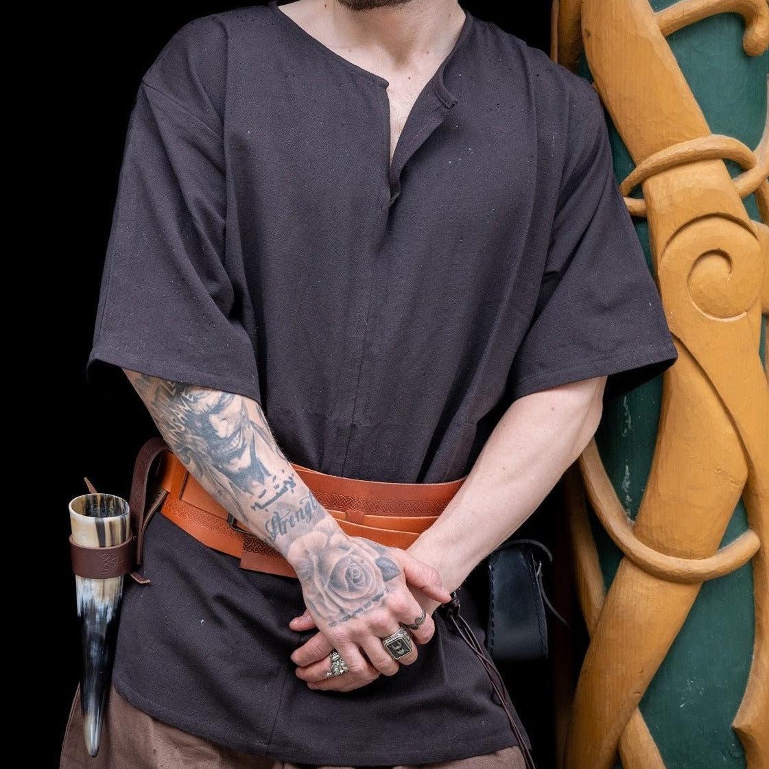 Renaissance black cotton short-sleeved tunic with brown leather belt, worn by a person with tattooed arms.