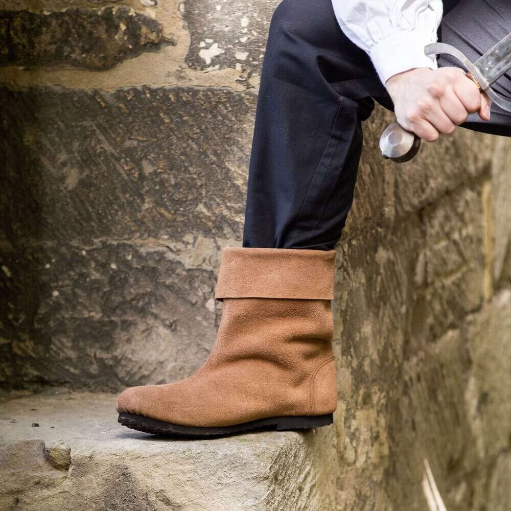 Renaissance brown suede Sigurd boots with a folded cuff and rubber sole, worn by a person in black pants.