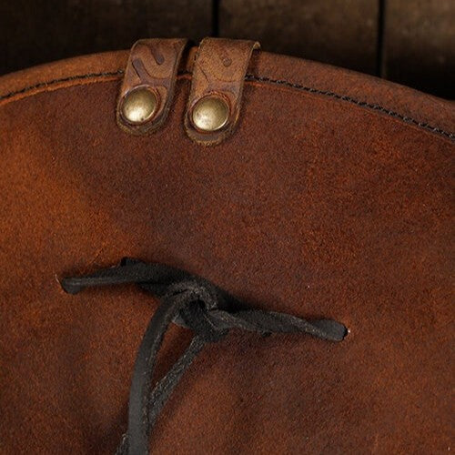 Close-up of a brown Renaissance leather tricorn hat with brass snaps and black lacing.