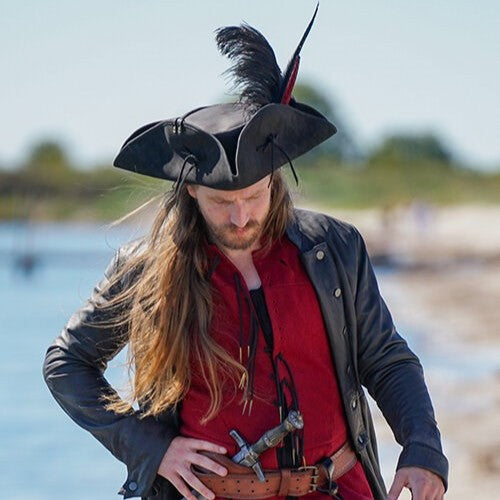 Man in black Renaissance leather tricorn hat with feather, red shirt, and black jacket.