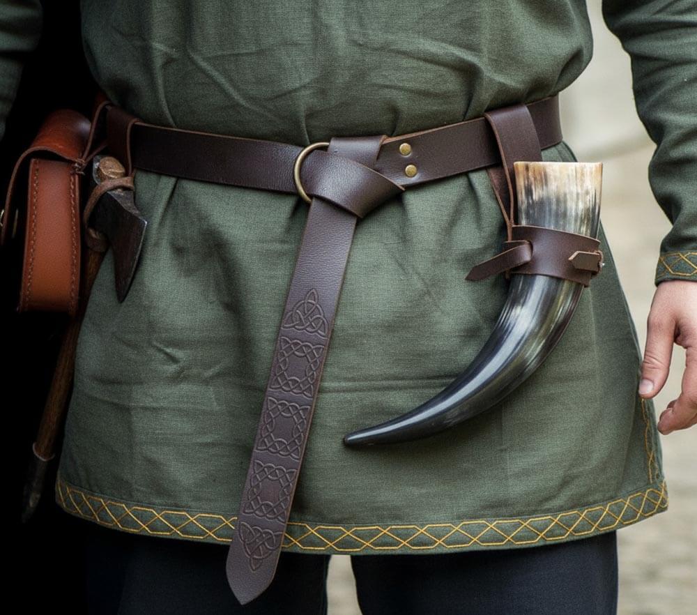 Person wearing a thick brown leather renaissance belt with ring loop and knot on a green tunic with horned accessory.