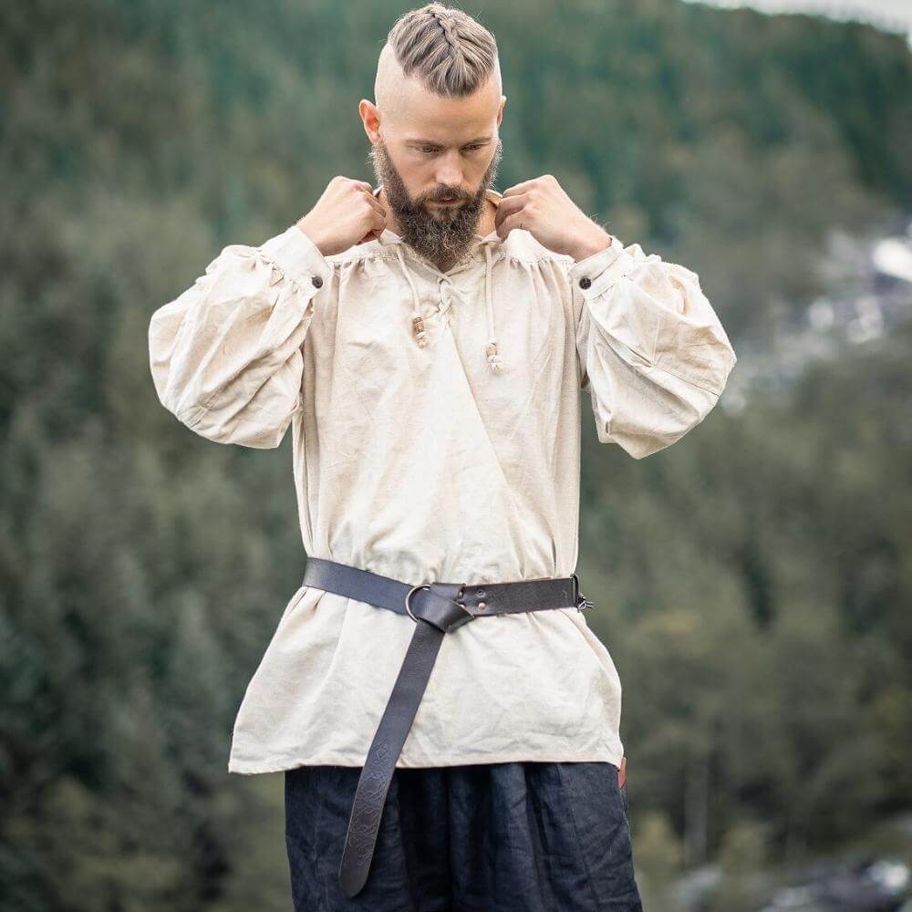 Man wearing a natural white Renaissance shirt with lace-up collar and full sleeves, belted at the waist outdoors.