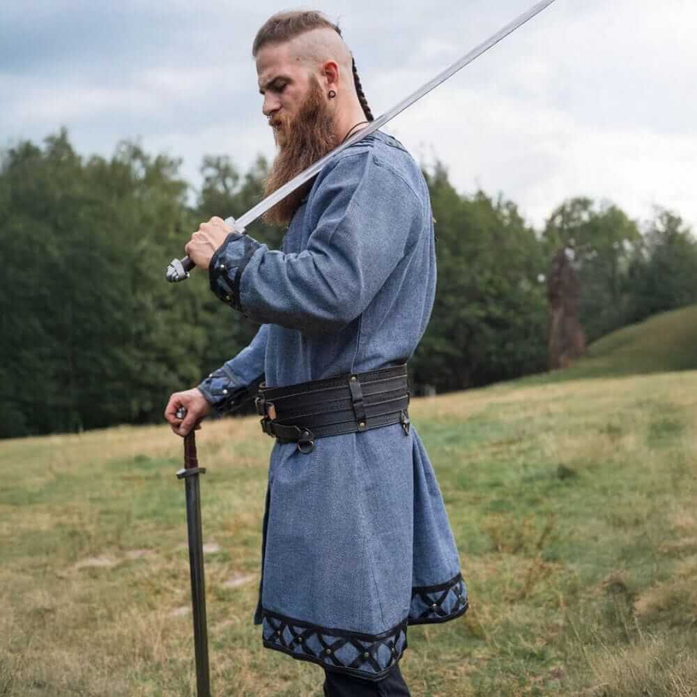 Blue-grey long-sleeve Renaissance tunic with leather accents and belt, worn by a man holding a sword.