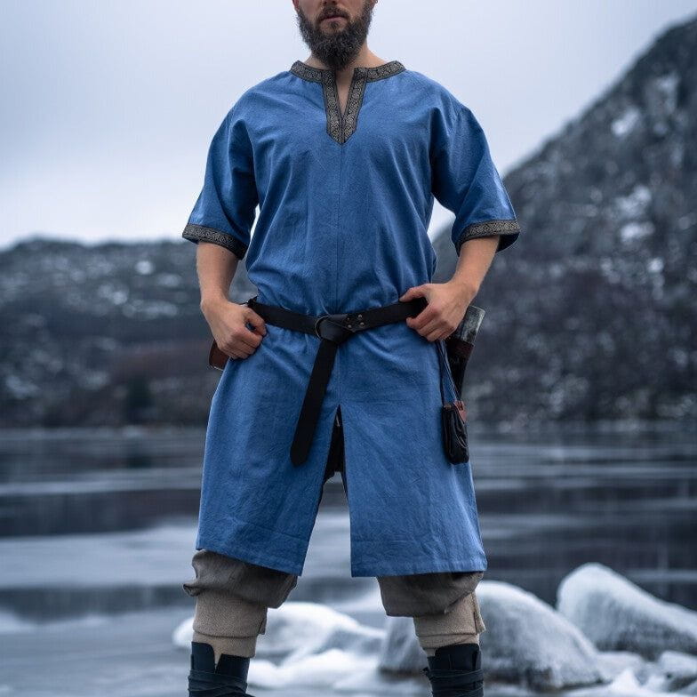 Blue Renaissance cotton tunic with embroidered V-neck and short sleeves, worn by a man outdoors.