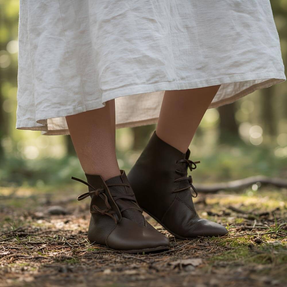 Brown leather Renaissance ankle boots with four-string adjustment, worn with a white linen dress.