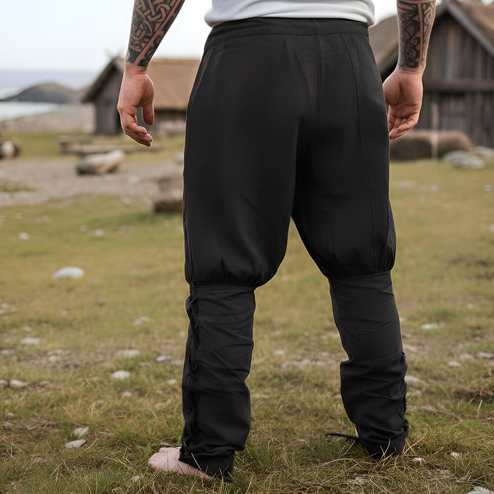 Black cotton Renaissance trousers with drawstring waist and calf lacing, worn by a person outdoors.