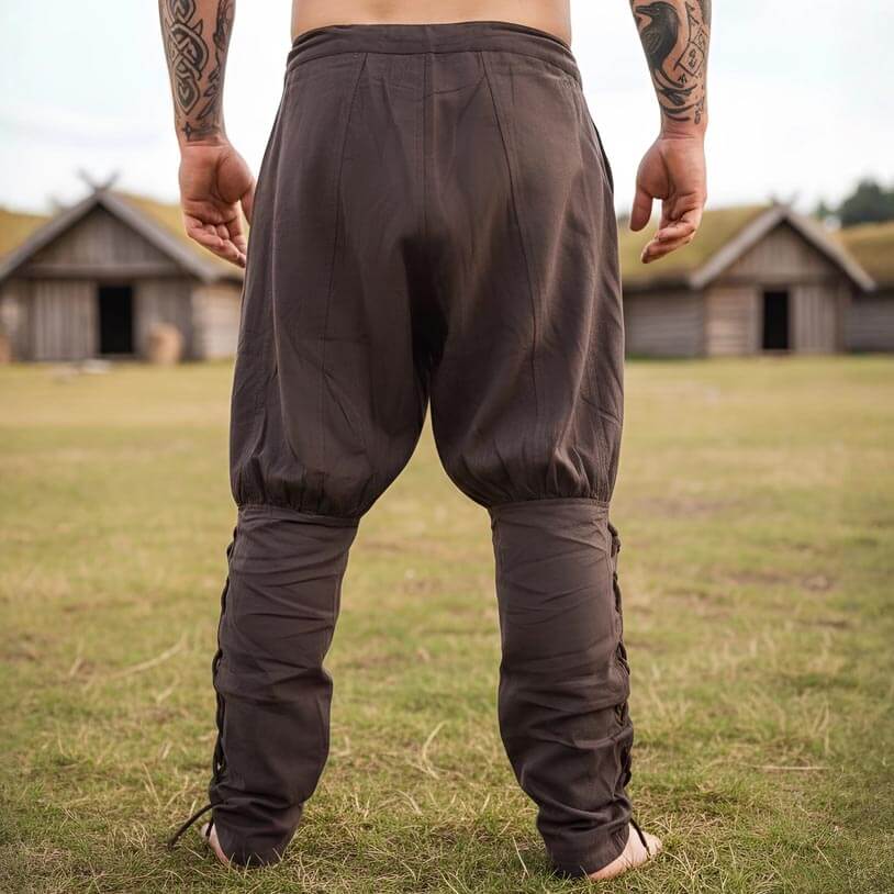Brown cotton Renaissance trousers with drawstring waist and calf lacing, worn outdoors.