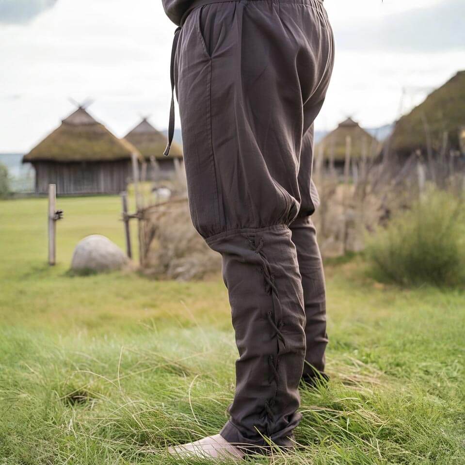 Brown cotton Renaissance trousers with drawstring waist and calf lacing, worn outdoors.