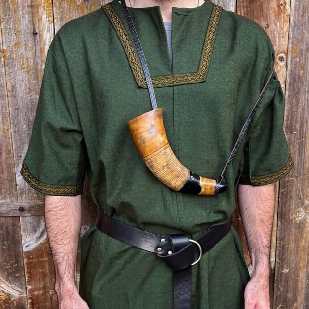 Renaissance blowing horn with a polished natural body, metal mouthpiece, and leather strap, worn over a green tunic.