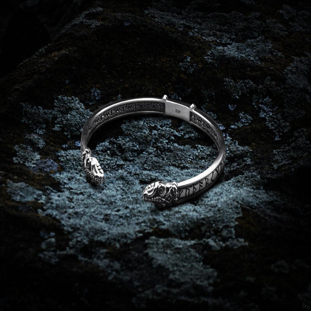 Sterling silver Renaissance Jormungandr serpent bracelet with Elder Futhark runes on dark rock.