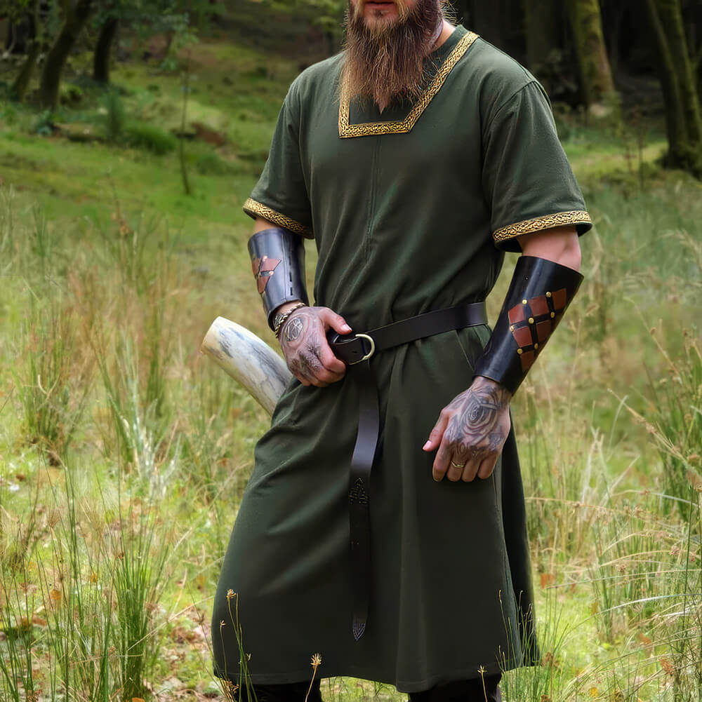 Renaissance short-sleeved green cotton tunic with gold embroidered trim, worn by a man in a forest.