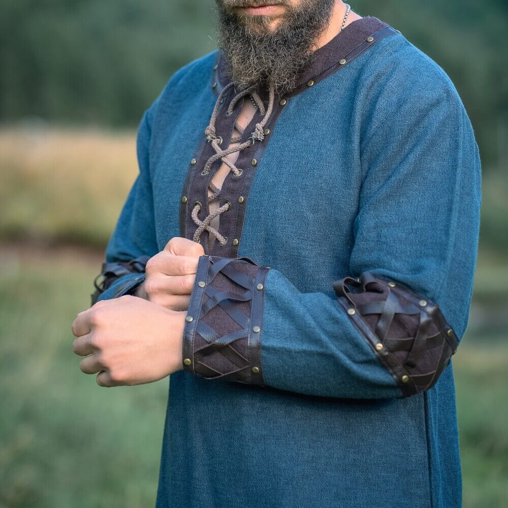 Blue Renaissance tunic with ornate leather trim, crisscross lacing, and riveted cuffs.
