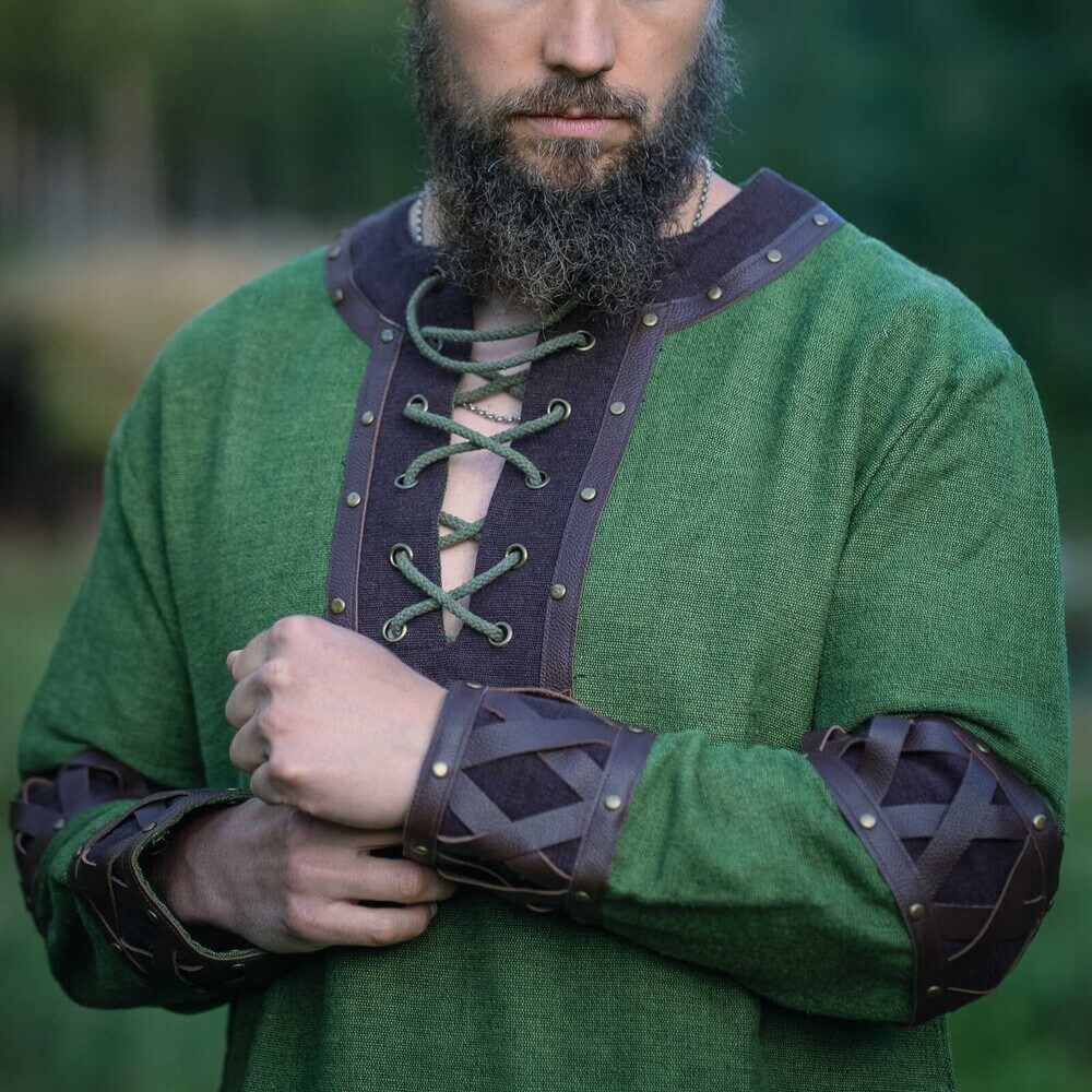 Renaissance green tunic with ornate crisscross leather trim, metal rivets, and X-pattern cuffs.