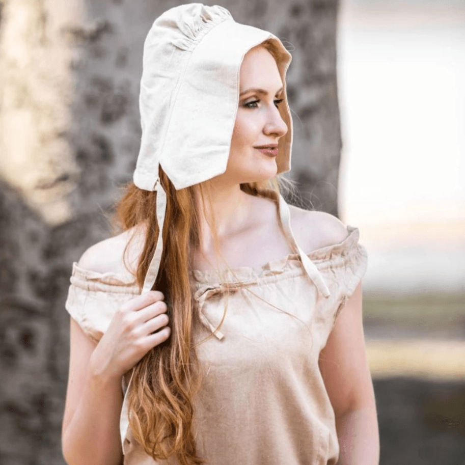 Woman wearing a natural cotton Renaissance bonnet with cord ties and an off-shoulder top.