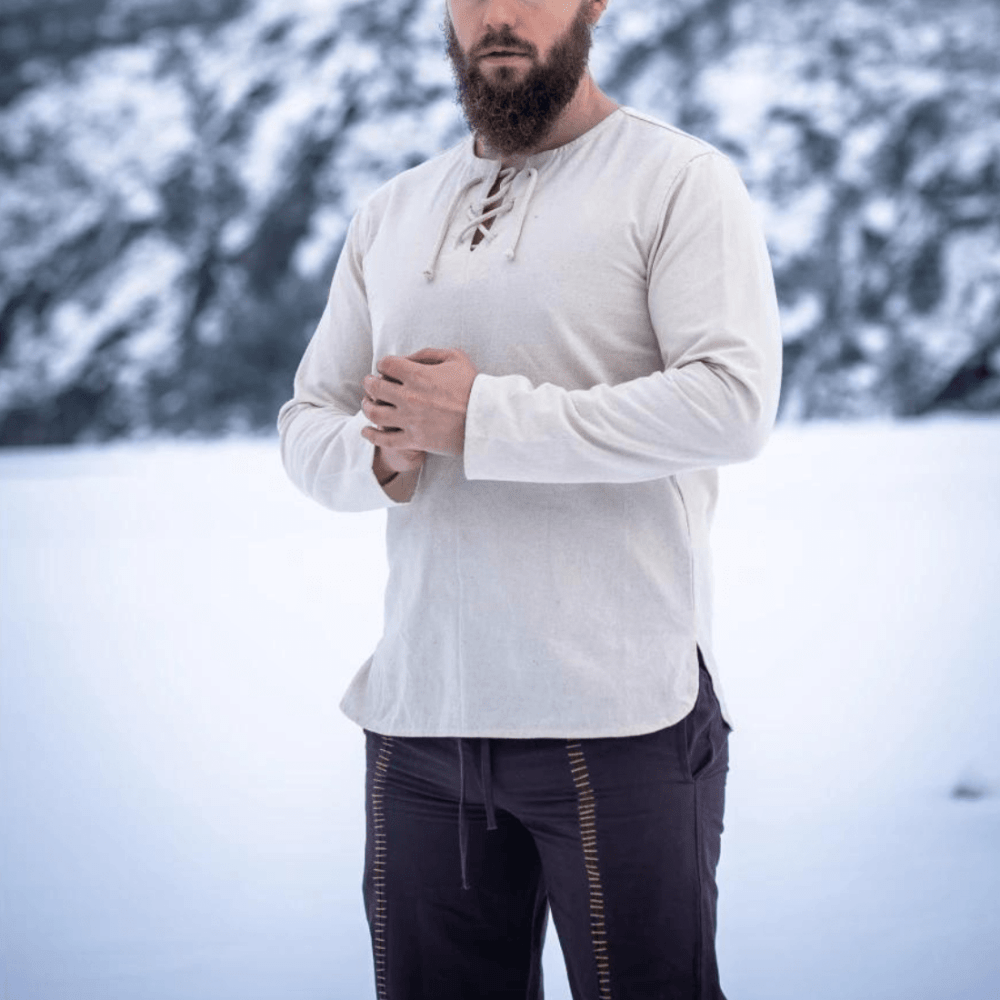 Renaissance natural cotton tunic with long sleeves and lace-up collar, worn by a man in snow.