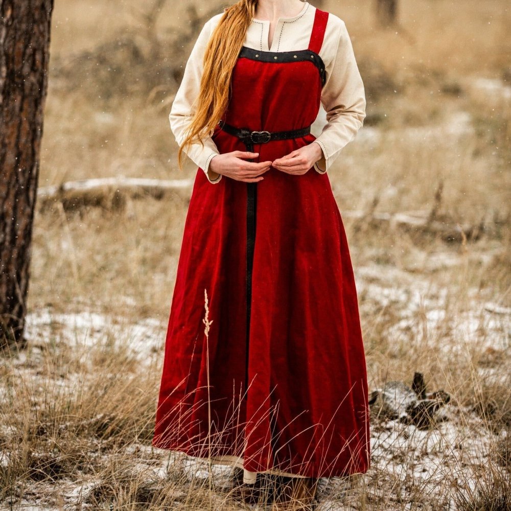 Red cotton Renaissance overdress with wide straps over a cream underdress, belted, in a snowy field.