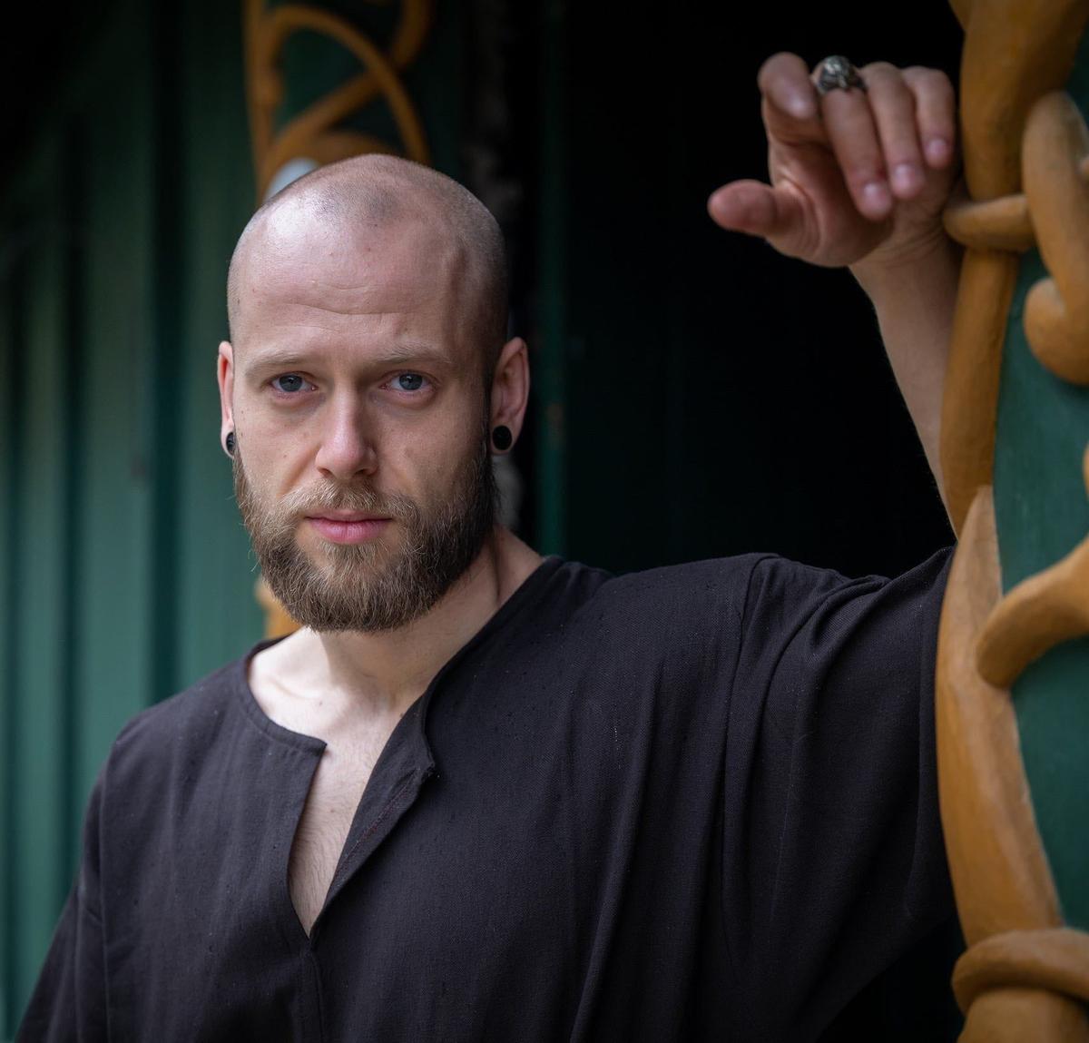 Man in a black Renaissance short-sleeved cotton tunic, hip-length, with a simple unadorned design.