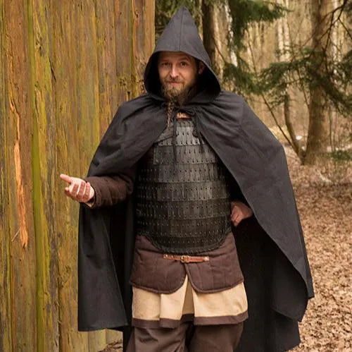 Renaissance black hooded war cloak of water-resistant cotton, worn over armor in a forest setting.
