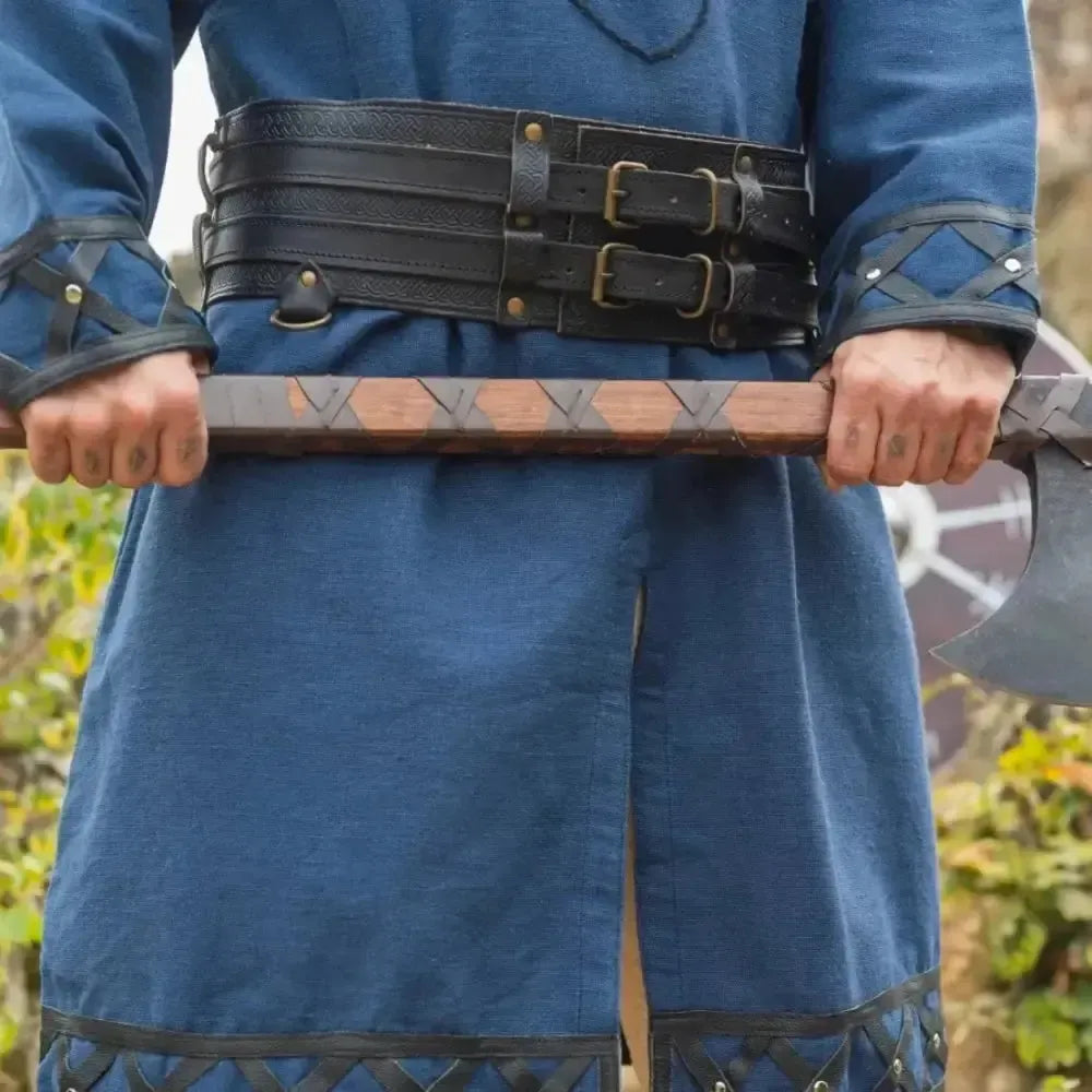 Renaissance black thick leather double belt with buckles worn over a blue tunic, holding an axe.