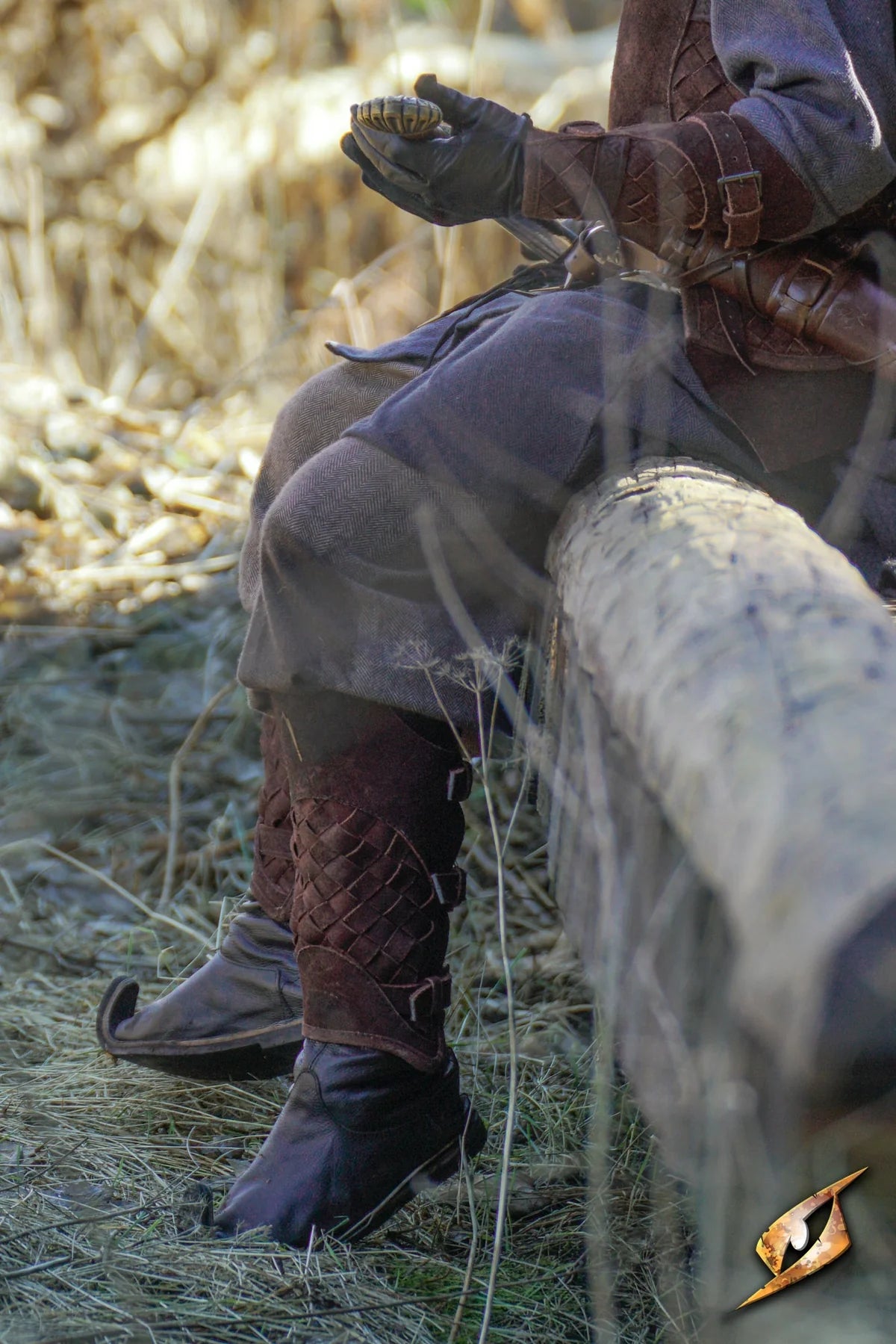 Renaissance woven brown leather greaves with brass buckles over black boots, worn by a reenactor.