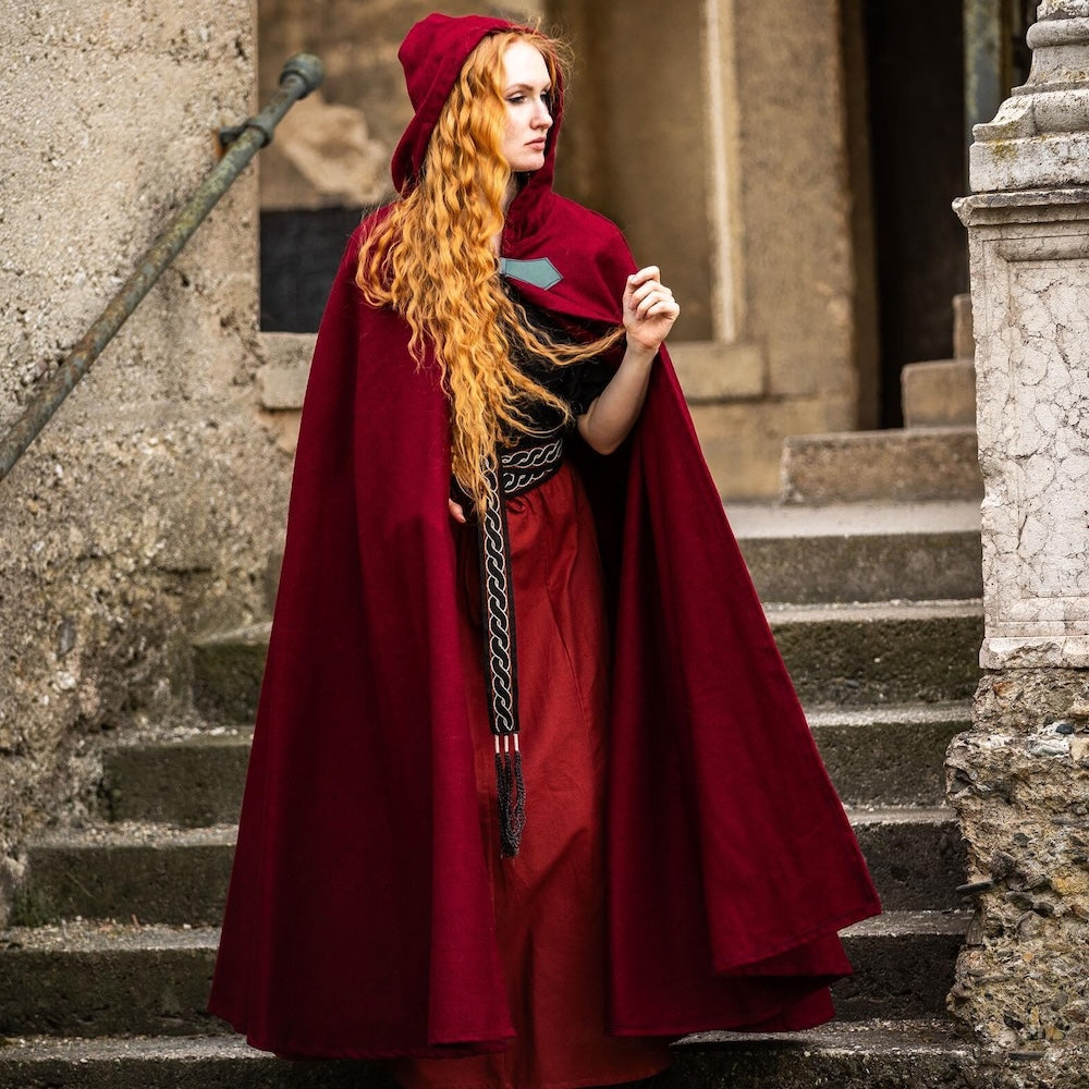 Metal wolf head clasp fastening a red wool cloak